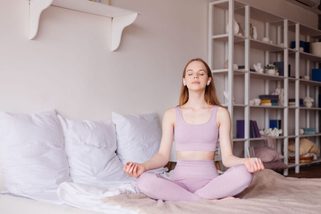 A peaceful woman practicing a 10-minute mindful morning routine at home, sitting calmly in meditation with sunlight streaming in